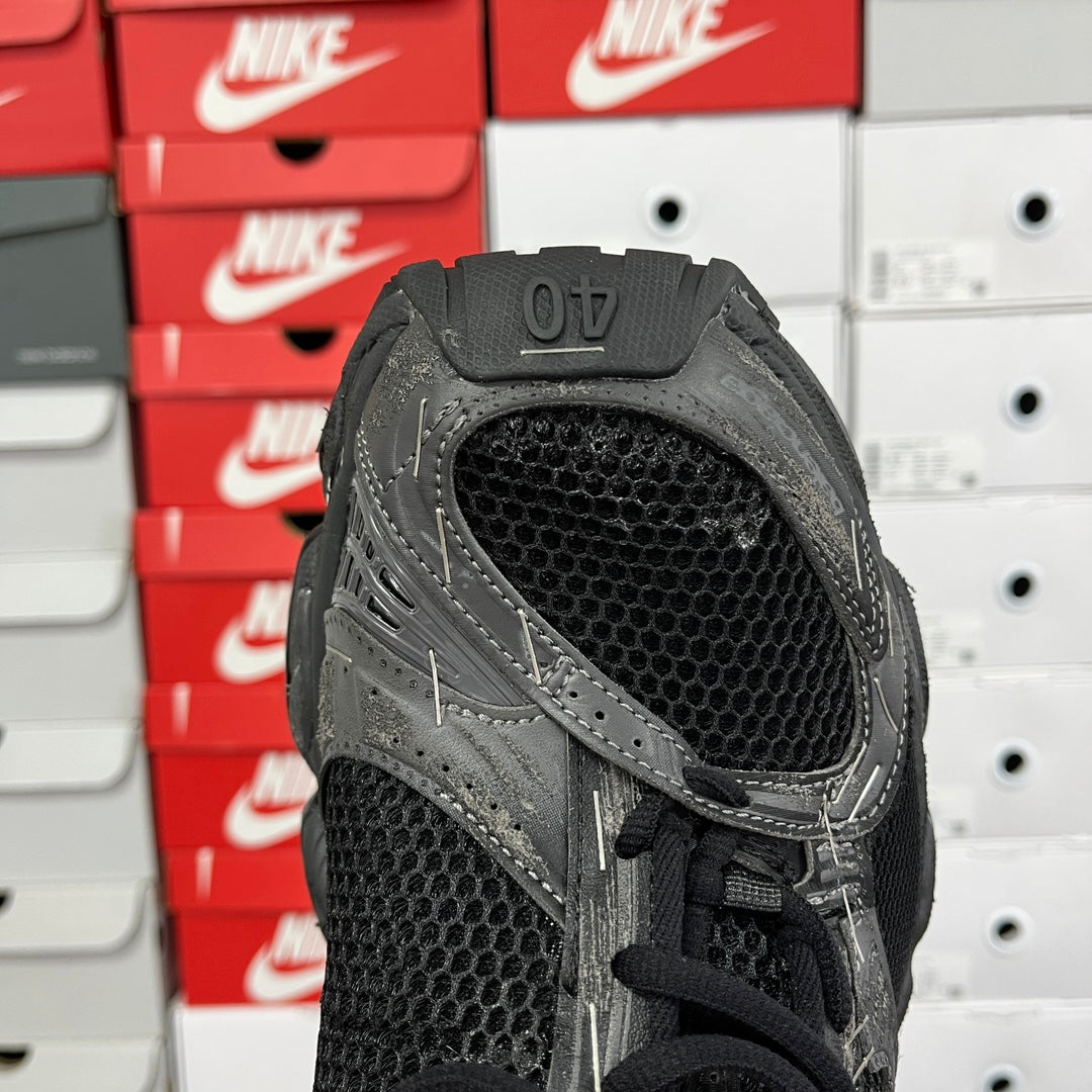 Black athletic sneaker with mesh collar and lace-up front, close-up heel view