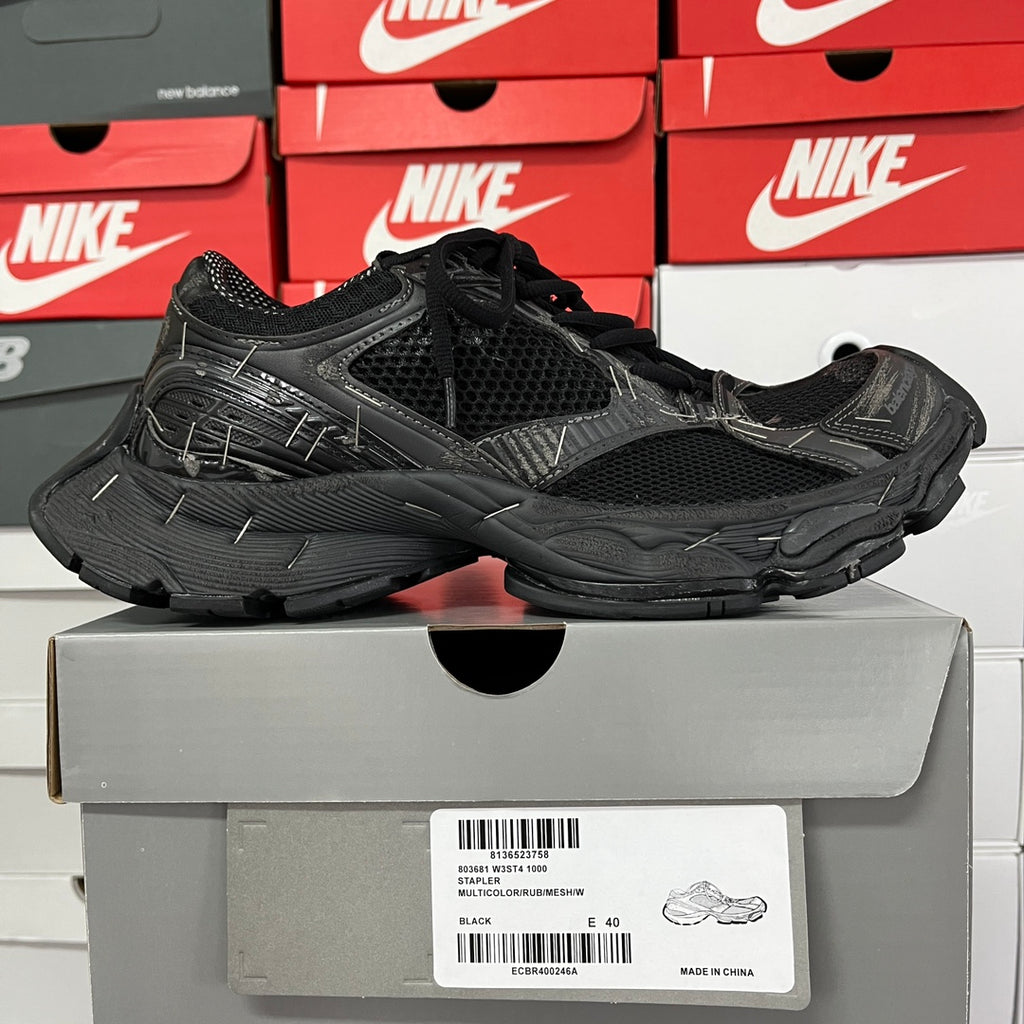 Black mesh athletic sneaker with layered overlays and black laces, on box view