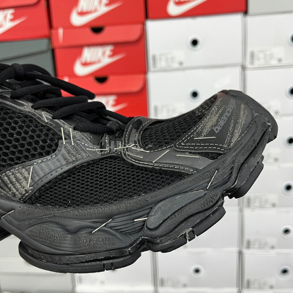 Black mesh athletic sneaker with stitched overlays and black laces, side close-up