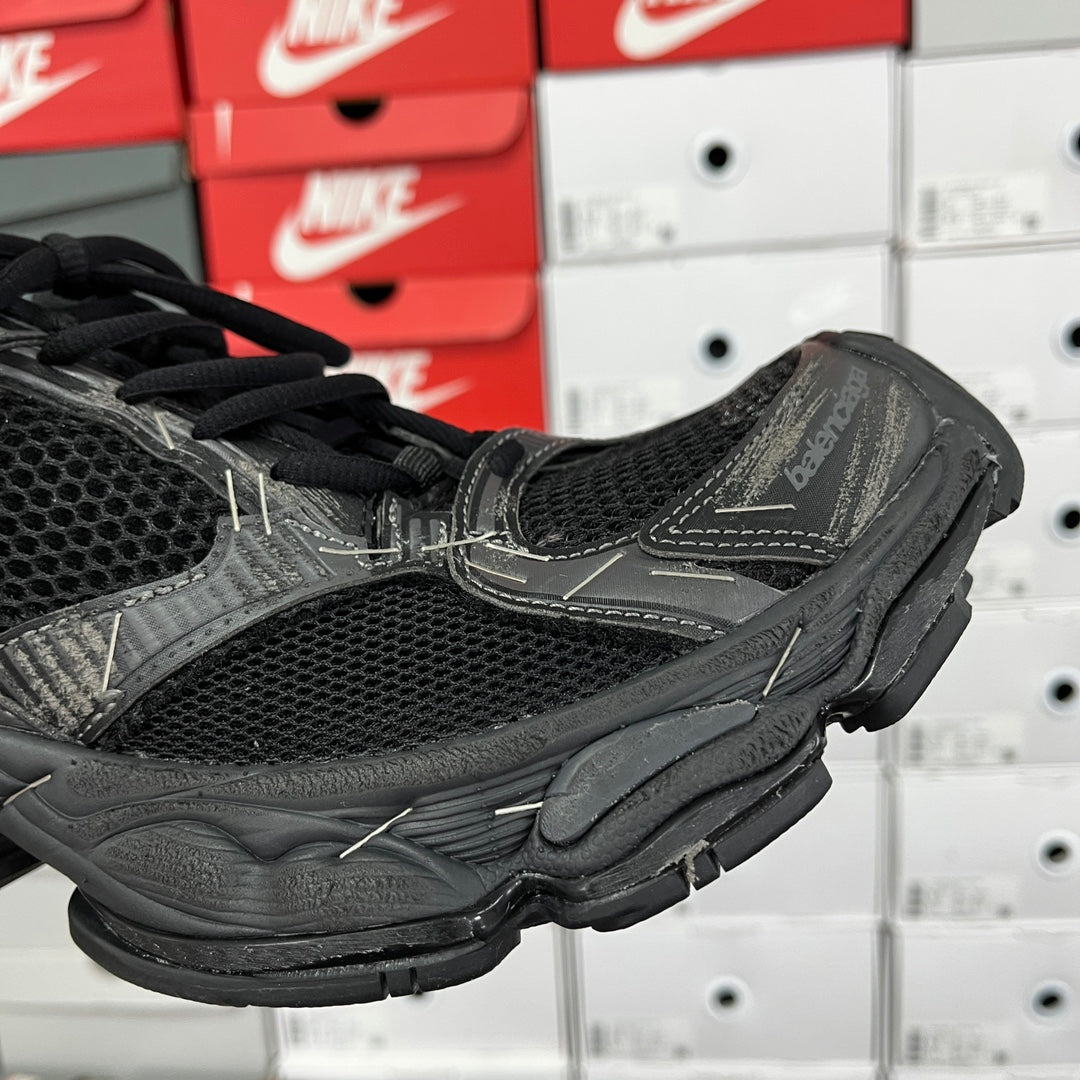Black mesh athletic sneaker with stitched overlays and black laces, side close-up