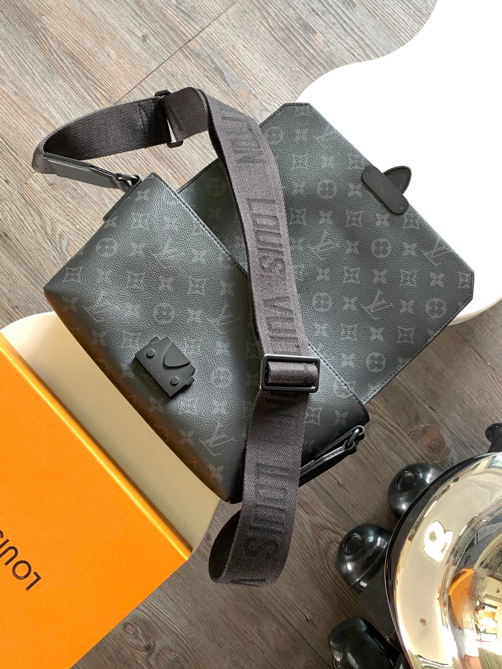 Louis Vuitton tote-style bag with flap, dual top handles, dark monogram canvas, strap.