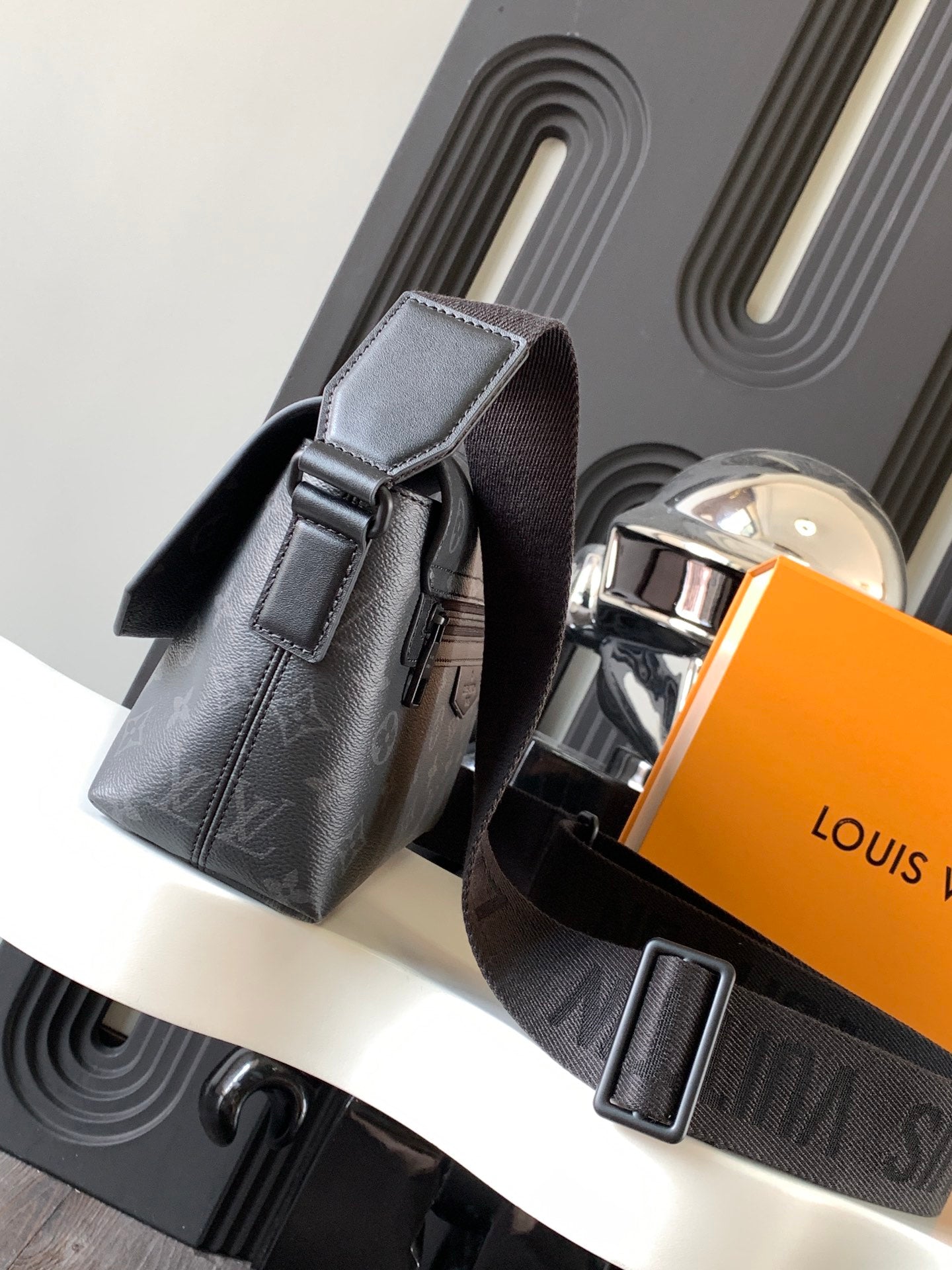 Louis Vuitton camera bag with flap, top handle, silver buckle, dark monogram canvas.