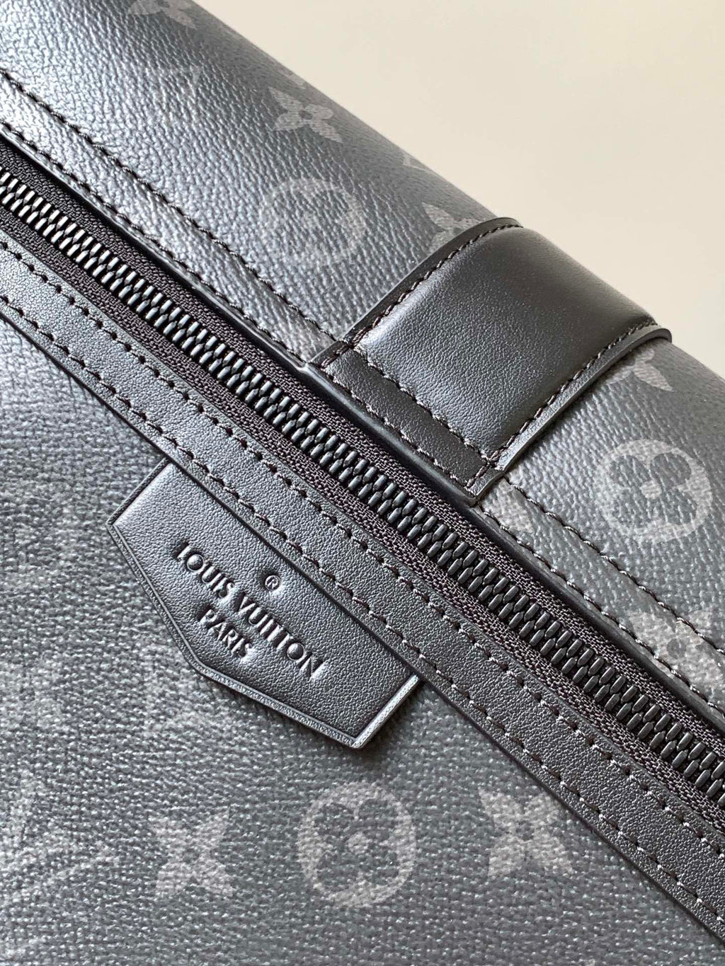 Louis Vuitton zipper pull and stitched leather trim on dark monogram canvas bag.