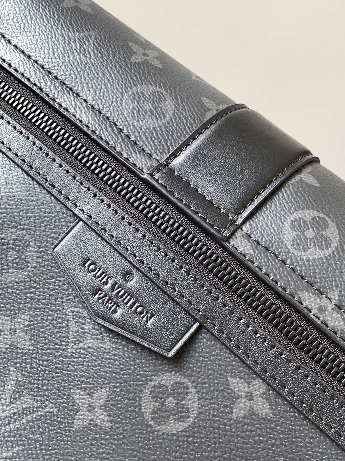 Louis Vuitton zipper pull and stitched leather trim on dark monogram canvas bag.