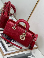 Dior red quilted handbag with top handle, front logo emblem, and shoulder strap