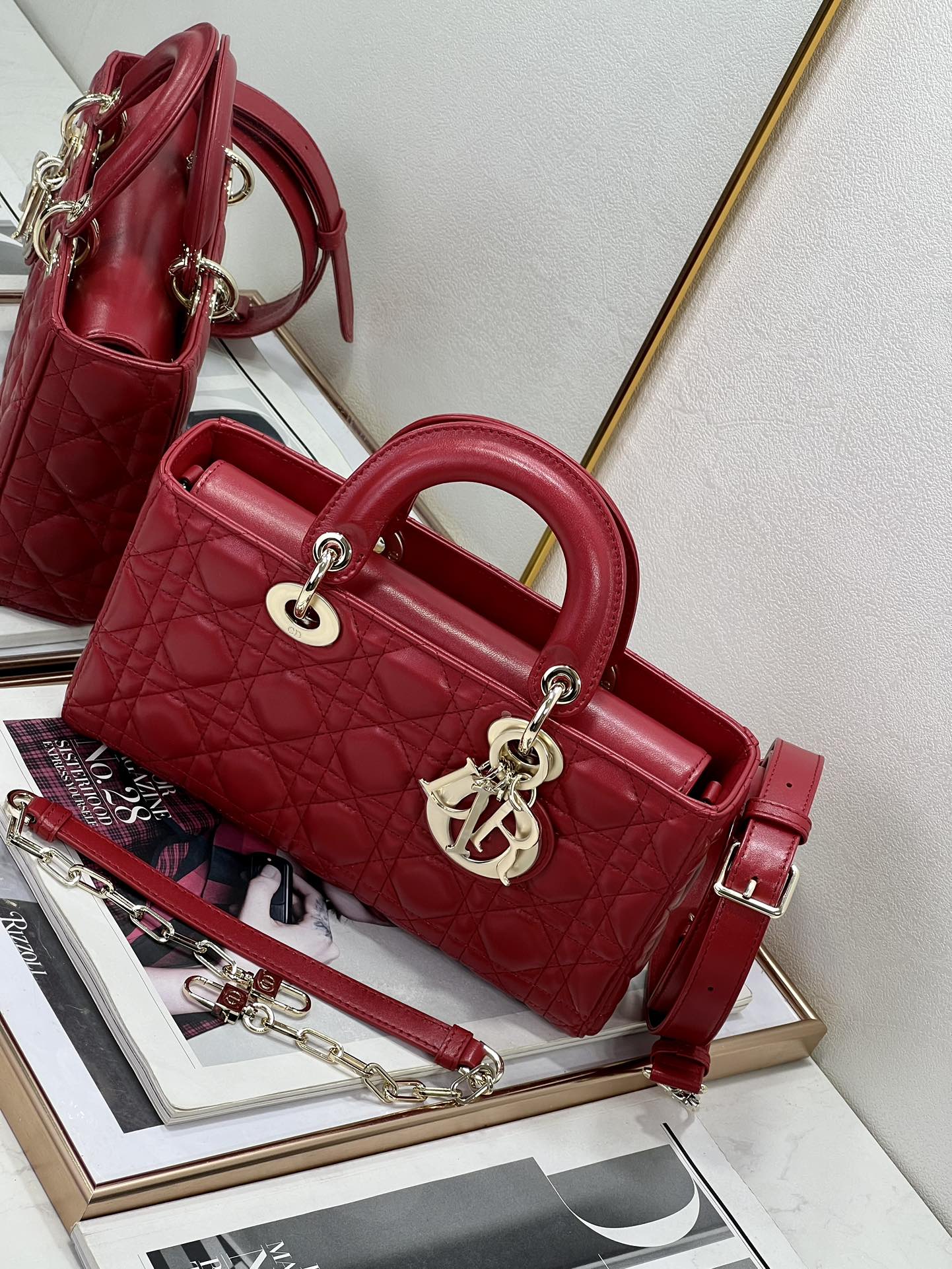 Dior red quilted handbag with top handle, front logo emblem, and shoulder strap