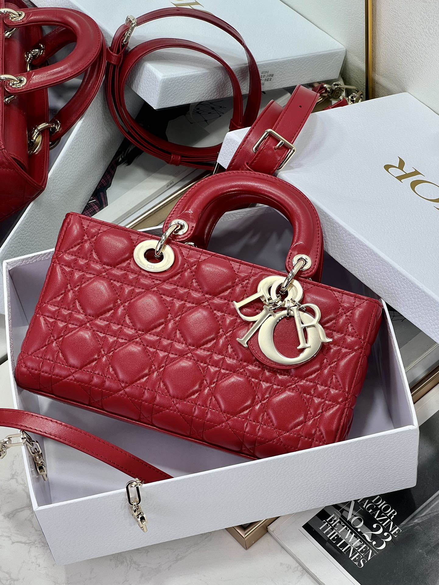 Dior red quilted handbag with top handles, front logo charm, and crossbody strap