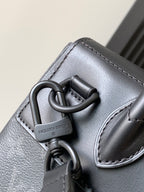 Louis Vuitton monogram handbag with leather patch, metal rings, dark gray.