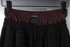 Black pants with elastic waistband and red plaid band featuring Balenciaga logo
