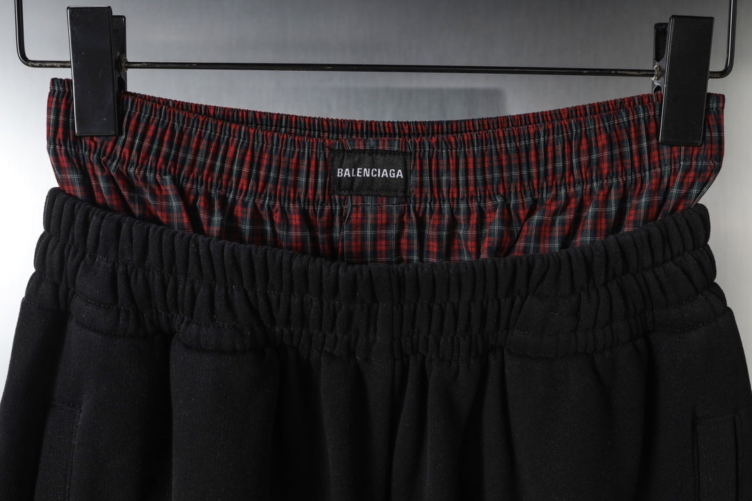 Black pants with elastic waistband and red plaid band featuring Balenciaga logo