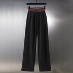 Black wide-leg pants with elastic waistband and red plaid inner band