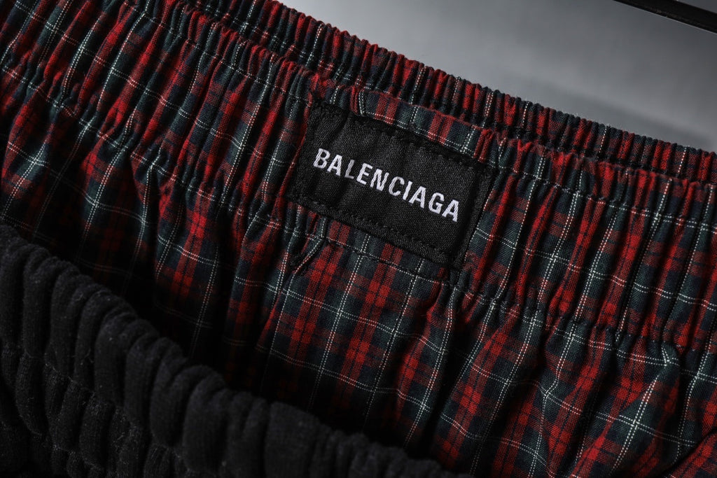 Balenciaga logo patch on red plaid waistband area of black pants