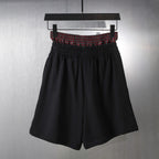 Black elastic-waist shorts with red plaid waistband trim