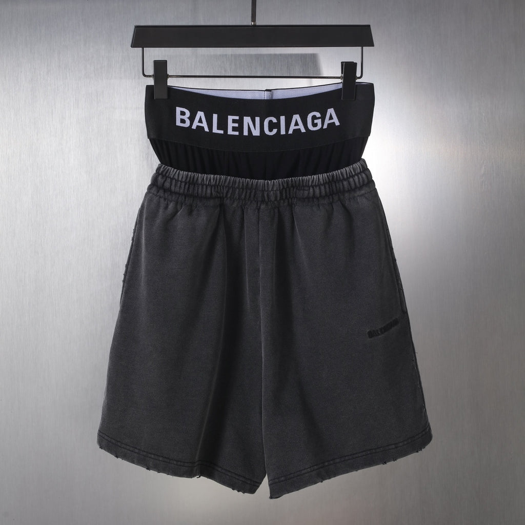 Black Balenciaga shorts with elastic waistband and front pleats, hanging on a hanger