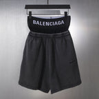 Black Balenciaga shorts with elastic waistband and front pleats, hanging on a hanger