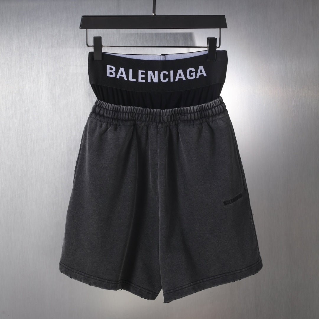 Black Balenciaga shorts with elastic waistband and front pleats, hanging on a hanger