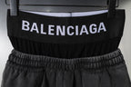 Black Balenciaga shorts with elastic waistband and logo band, close-up view on hanger