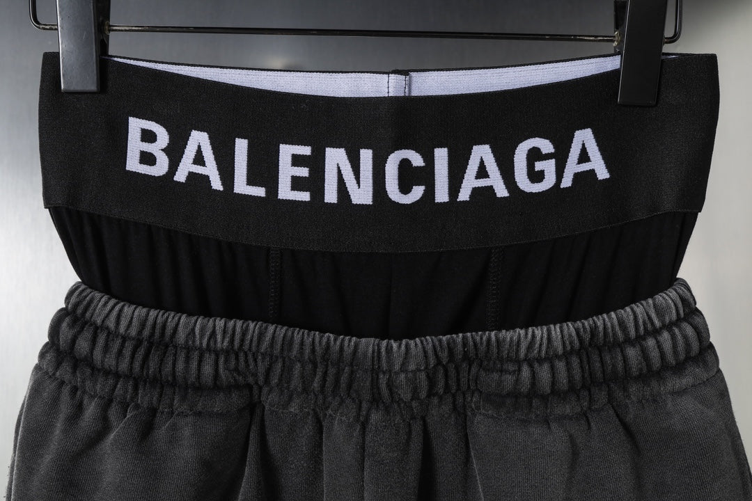 Black Balenciaga shorts with elastic waistband and logo band, close-up view on hanger