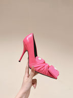 Pink stiletto sandal held up, showing pointed toe and black interior lining