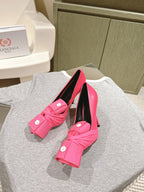 Pink sandals with twisted front straps, white button accents, black interior, stiletto heel