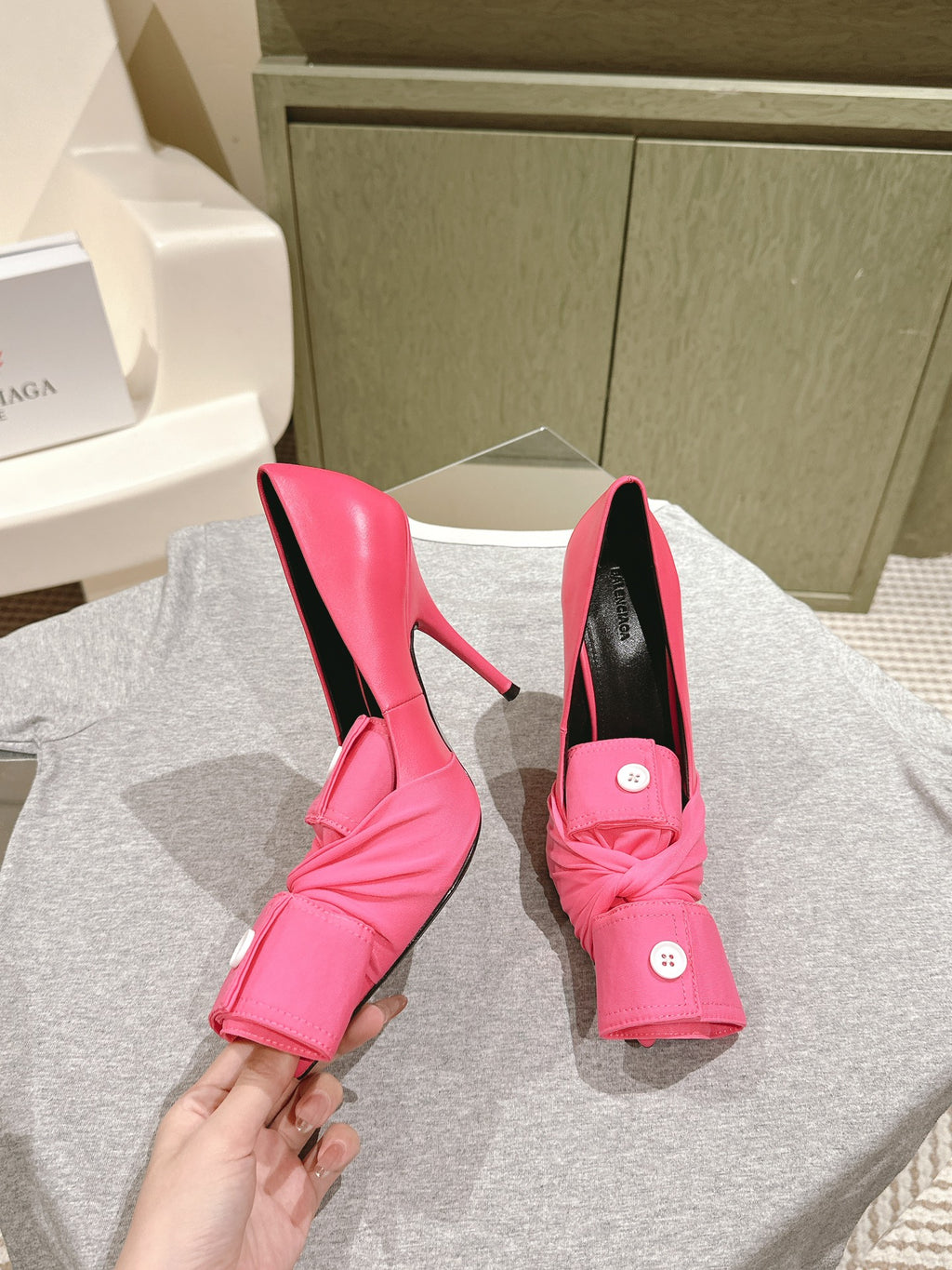 Pair of pink stiletto sandals with knotted front straps and black footbed