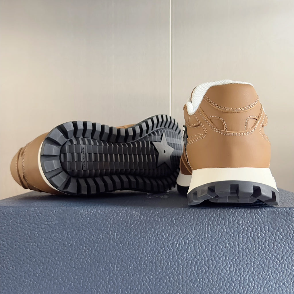 Tan sneaker outsole view with black tread and heel, white midsole