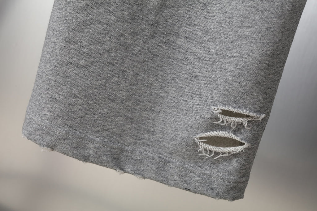 Grey sweatpants hem with frayed distressed knee rip detail