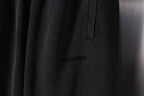 Black pants with vertical pocket flap and small stitched logo on the leg