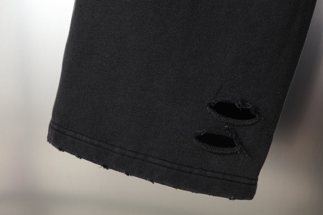 Black pants with distressed hem and cutout openings at cuff