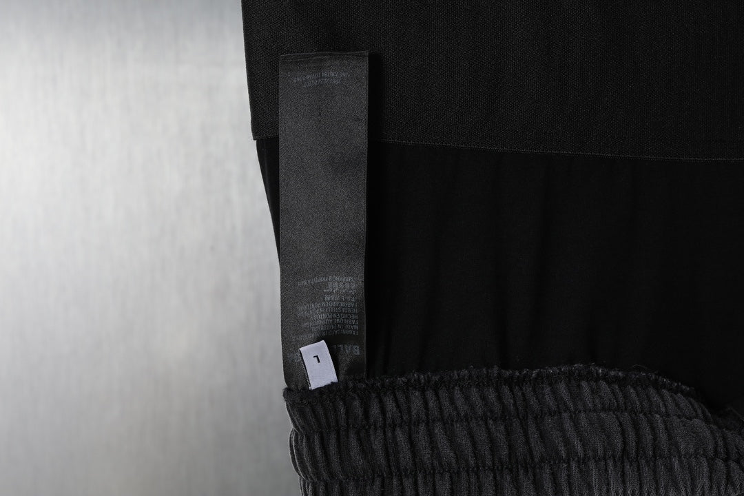 Black pants leg with side pocket seam and a hanging tag near the waistband