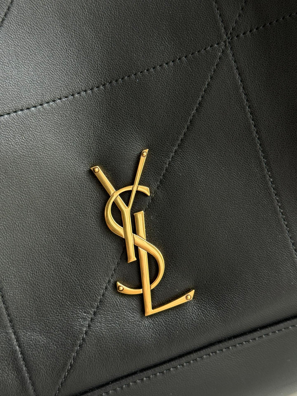 YSL logo emblem in gold on dark navy leather with diamond quilting