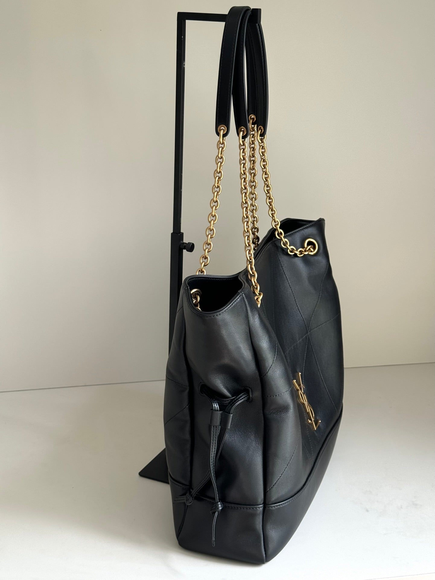 YSL tote bag side view in dark navy leather with gold chains and drawstring ties