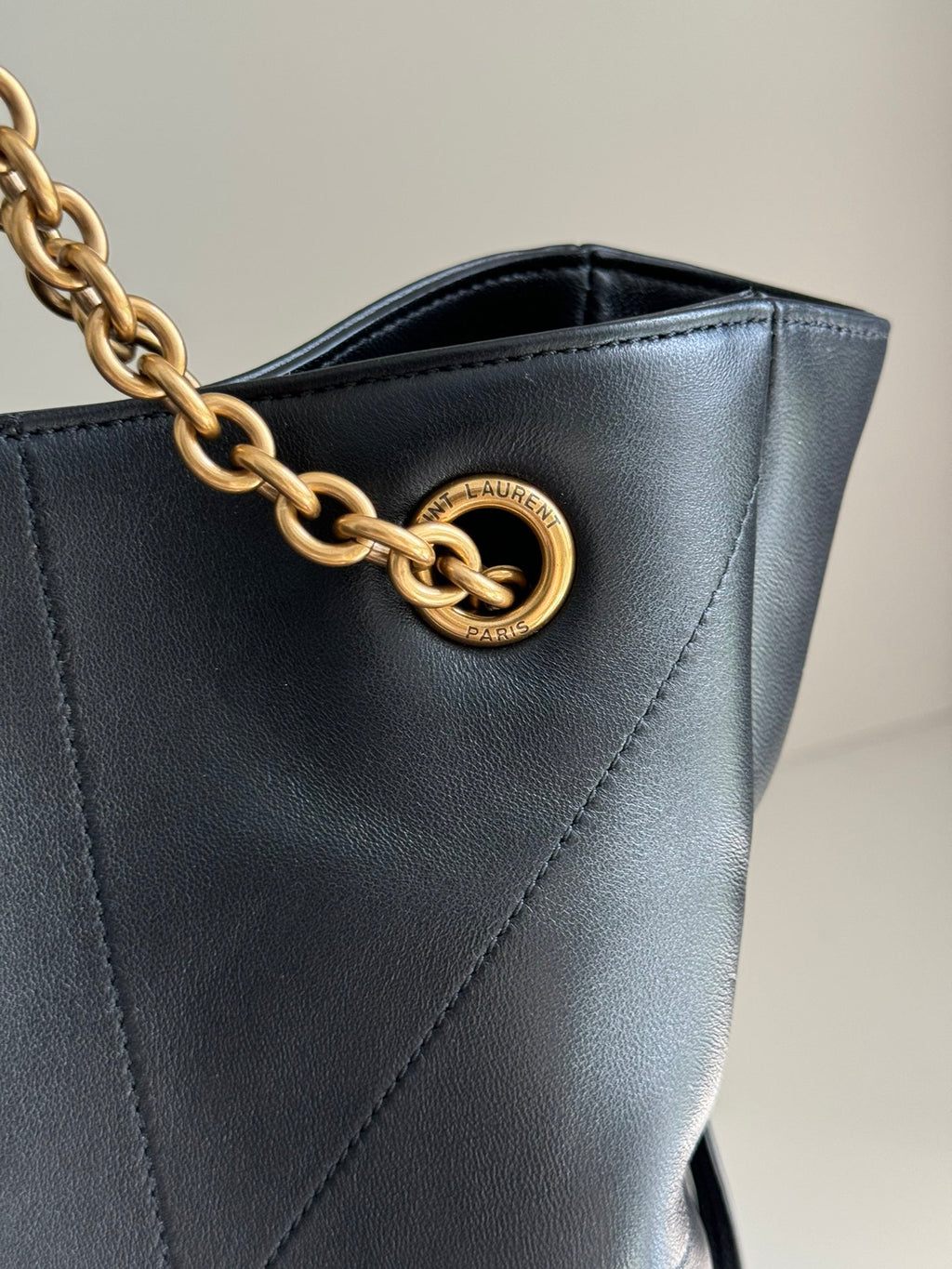 YSL bag close-up: gold YSL monogram on dark navy leather with quilted stitching