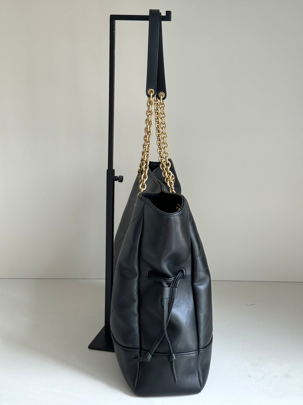 YSL tote bag angled view in dark navy leather with gold chain shoulder strap