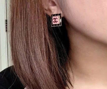 Square Chanel logo stud earring with pink enamel center, close to face