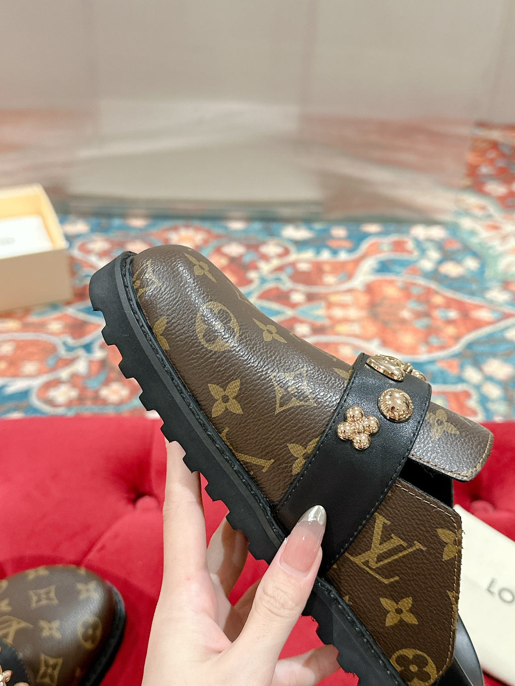 Louis Vuitton monogram slide sandal with gold-tone emblem hardware on black strap.