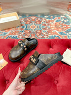 Louis Vuitton monogram slide sandals, black with gold-tone emblem buckles and strap.