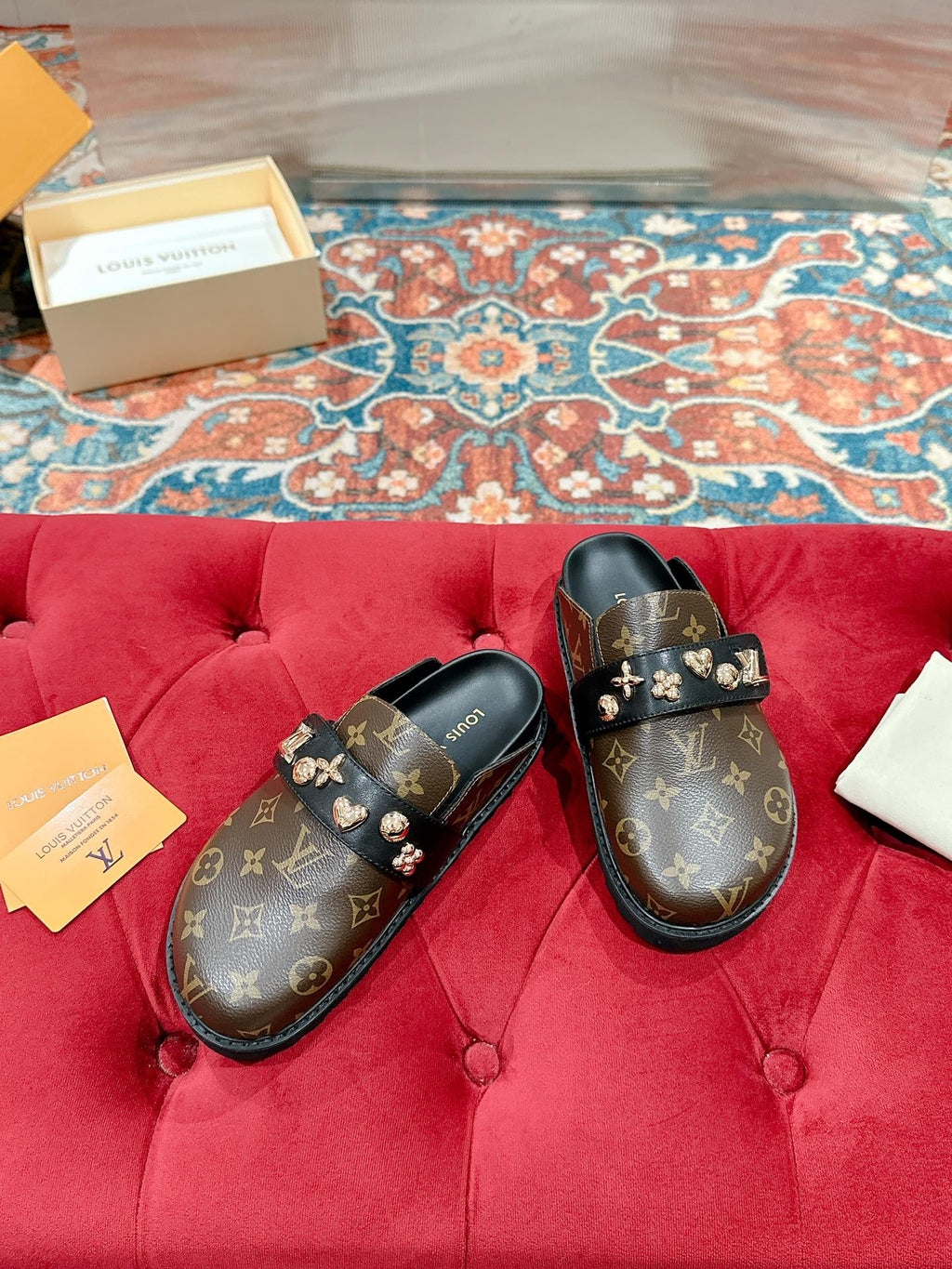Louis Vuitton monogram slide sandals, black with gold-tone emblem detail on straps.