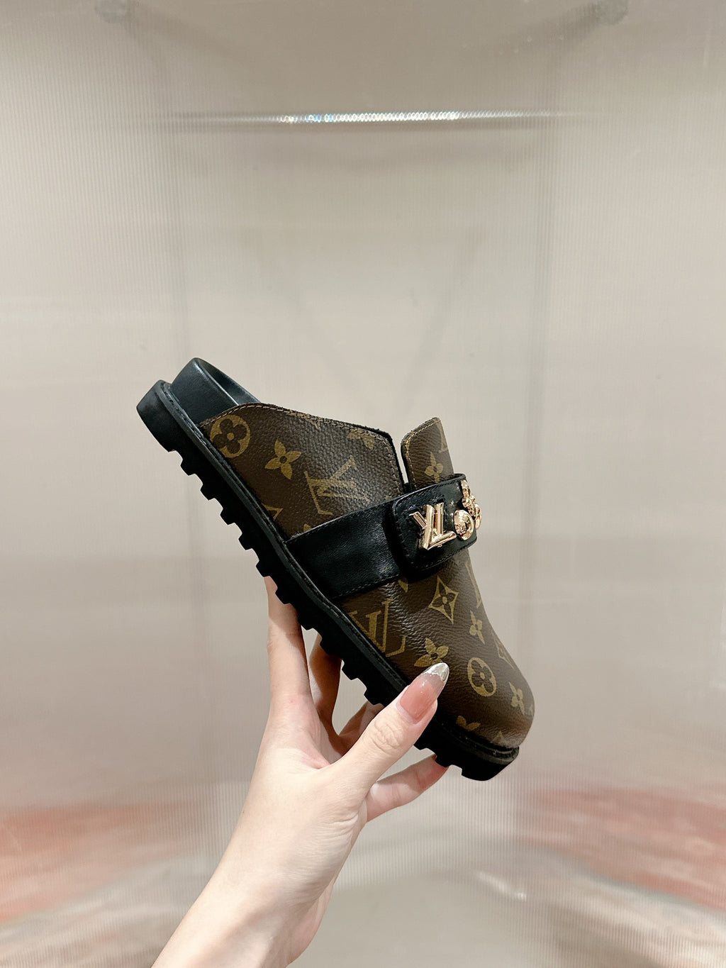Louis Vuitton monogram slide sandal with black strap and gold-tone buckle hardware.