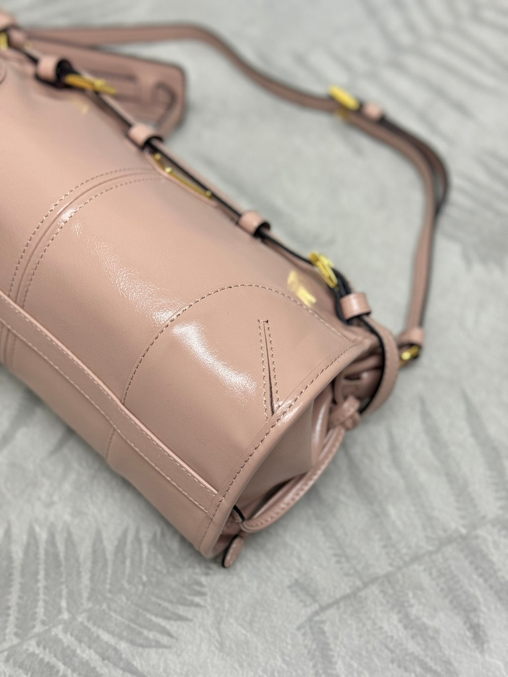 Pink leather handbag corner with metal strap ring and smooth panel stitching