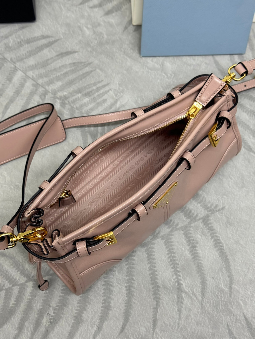 Pink leather handbag with open top showing patterned lining and gold-tone zipper