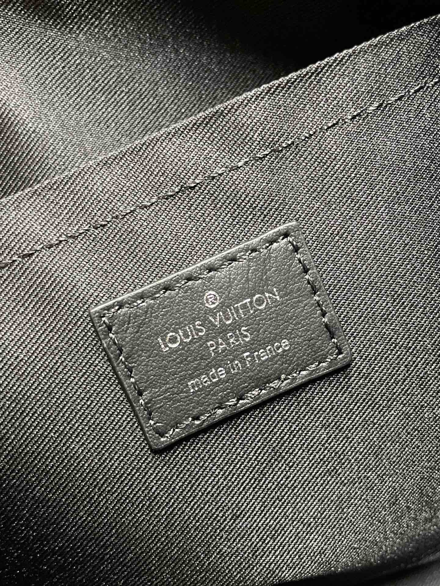 Leather brand label reading Louis Vuitton on monogram canvas bag