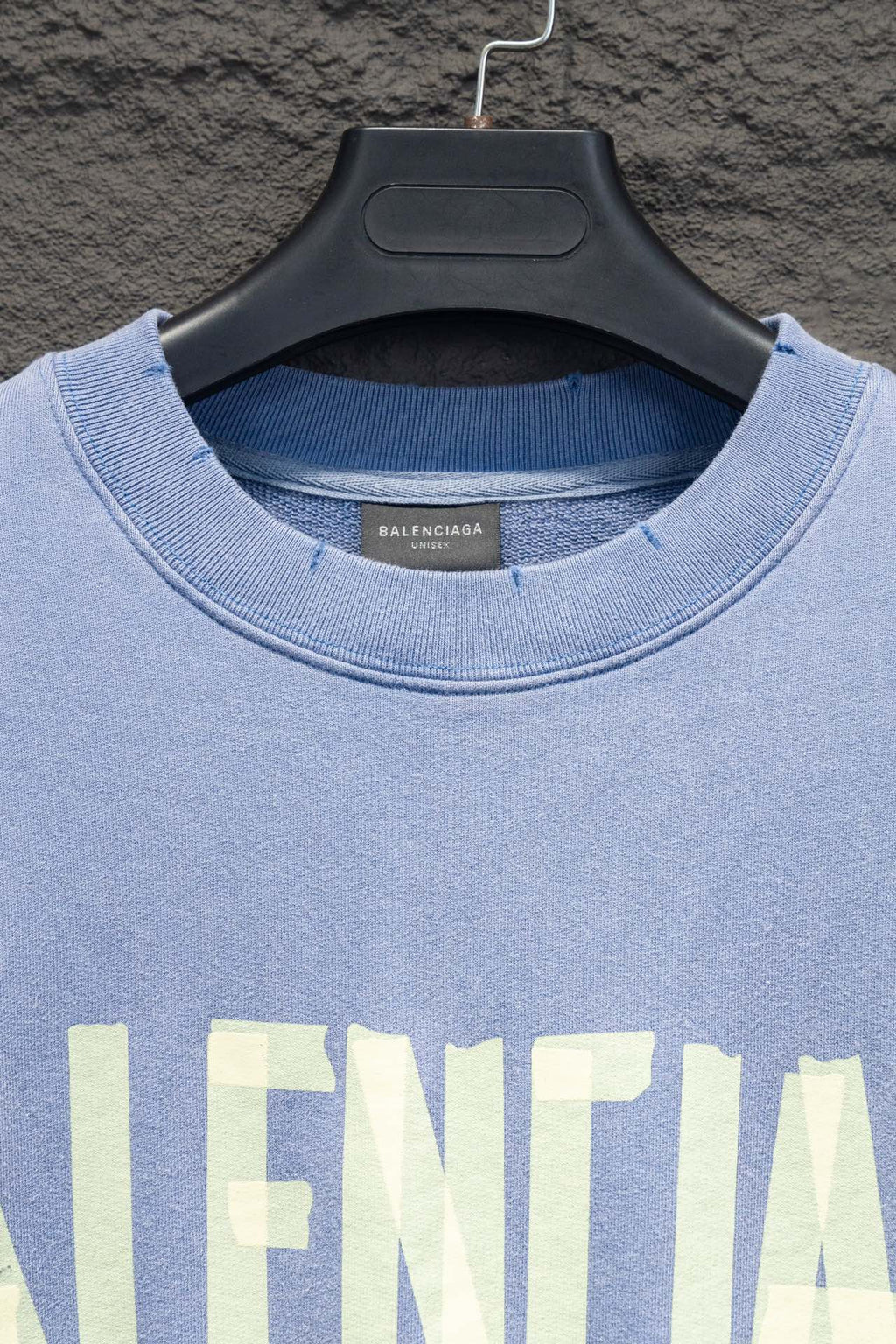 Light blue sweatshirt neckline with ribbed collar and partial Balenciaga print.