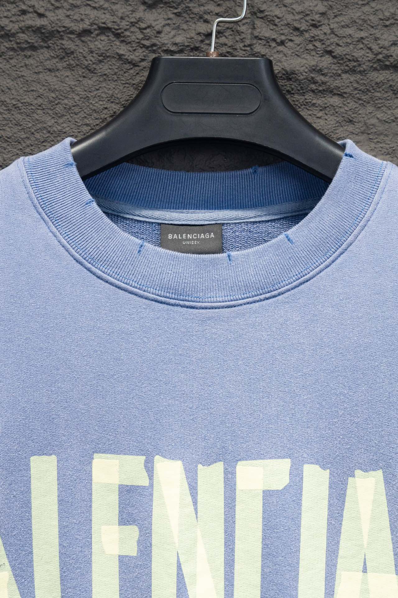 Light blue sweatshirt neckline with ribbed collar and partial Balenciaga print.