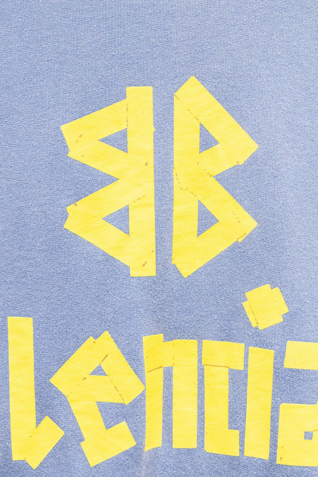 Light blue sweatshirt close-up of yellow graphic and Balenciaga wordmark text.