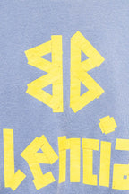 Light blue sweatshirt close-up of yellow graphic and Balenciaga wordmark text.
