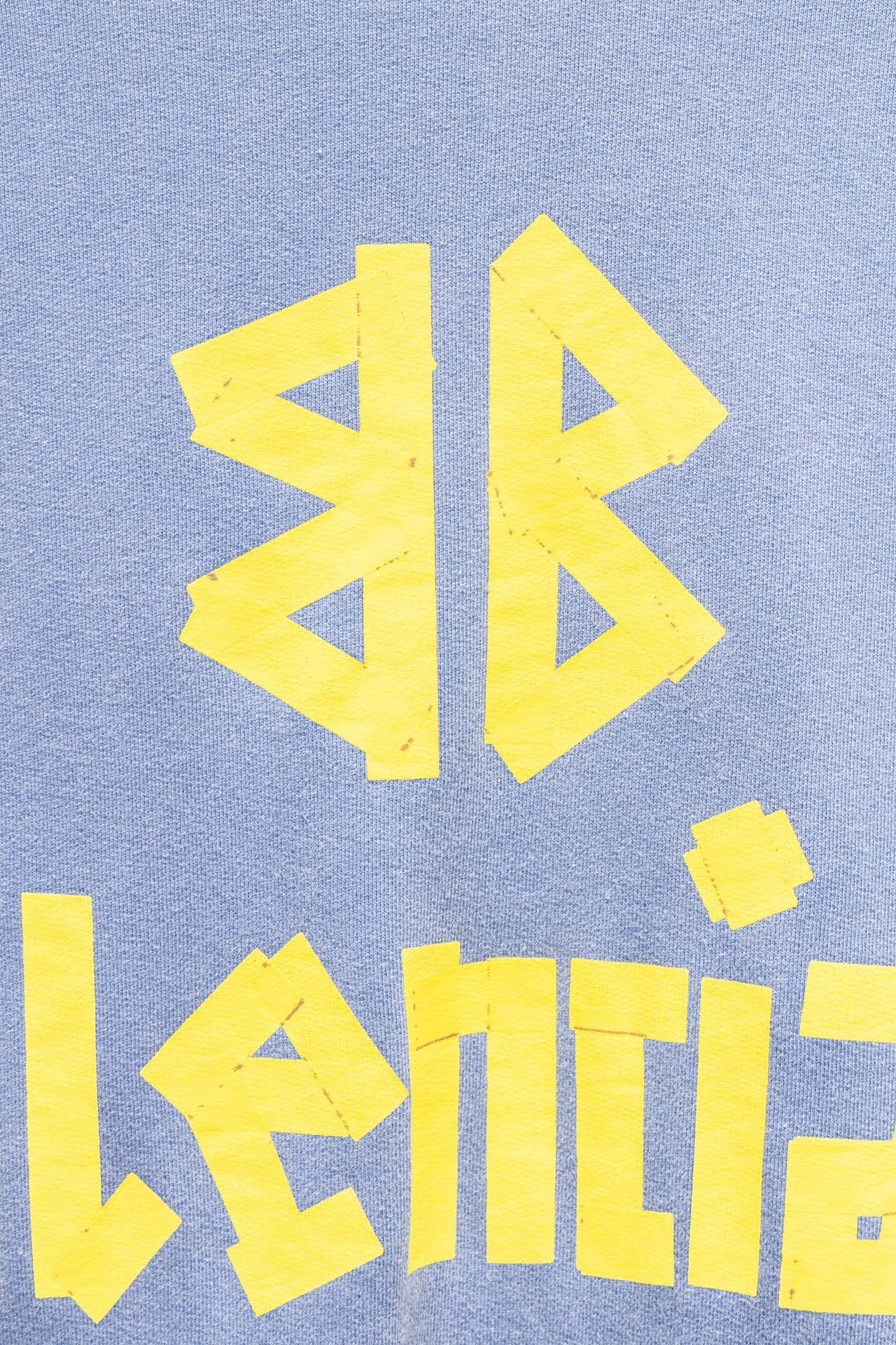 Light blue sweatshirt close-up of yellow graphic and Balenciaga wordmark text.
