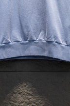 Light blue sweatshirt hem with ribbed band and stitched seam detail.