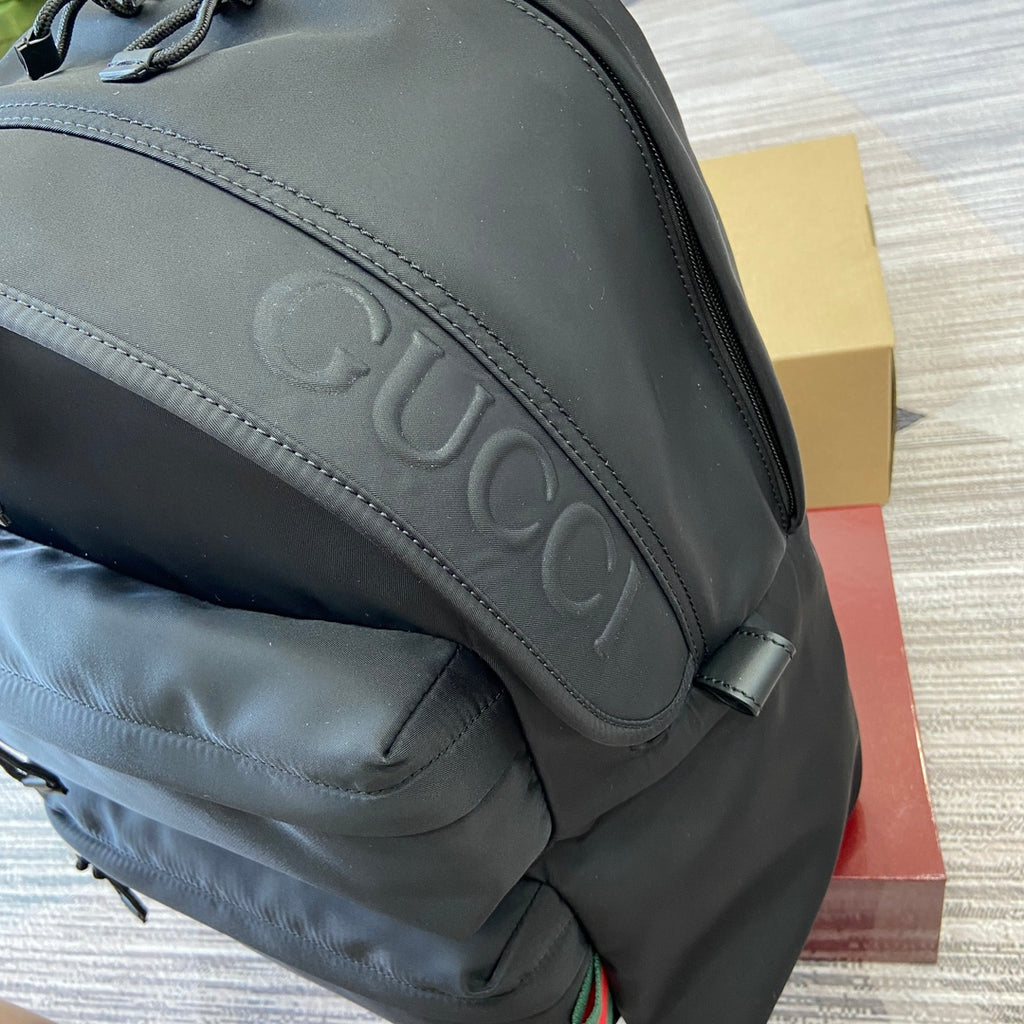 Gray Gucci backpack front logo panel with embossed lettering and stitched trim