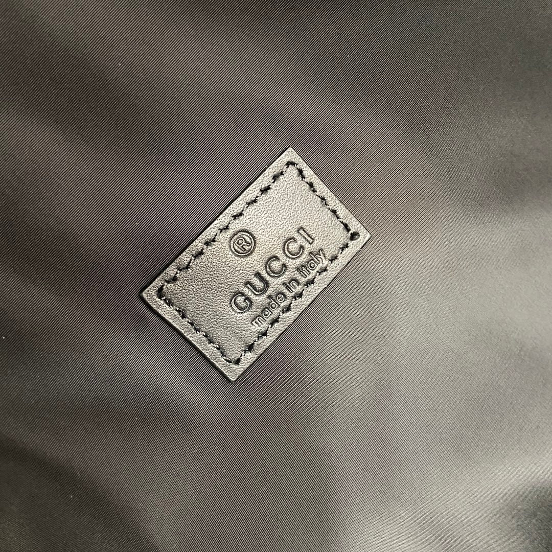 Gucci logo fabric tag on dark gray backpack with border stitching